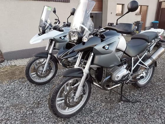 Dwa motory koloru srebrnego marki BMW stojące przed budynkiem.